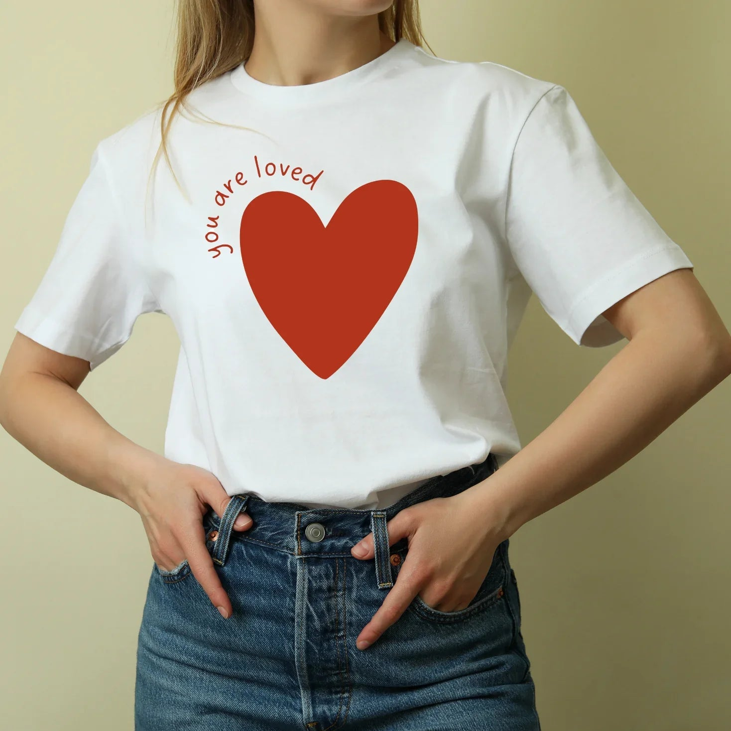 Woman wearing Jackalo white t-shirt with red heart and 'you are loved' text, sustainable kids clothing