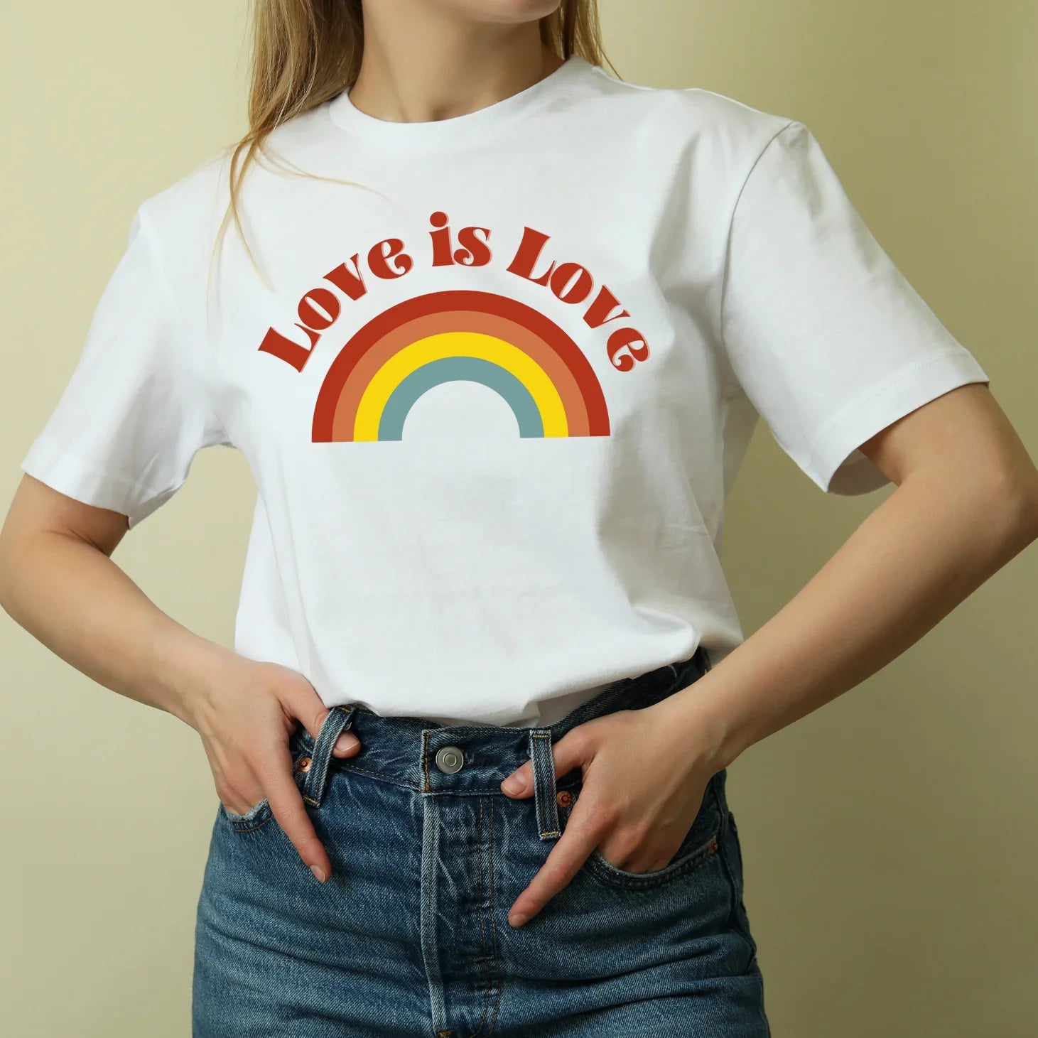 Woman wearing Jackalo white t-shirt with 'Love is Love' rainbow print, sustainable clothing
