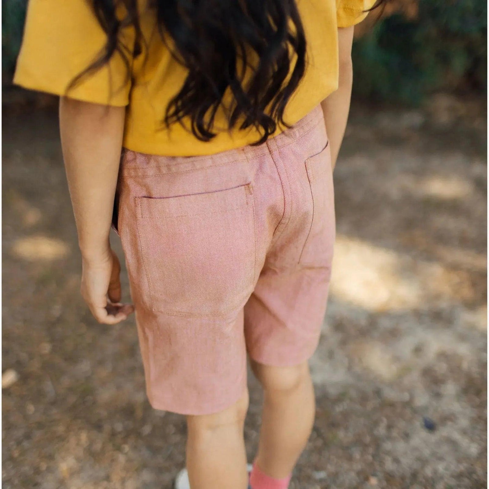 Child in yellow shirt and pink shorts outdoors wearing Jackalo sustainable kids clothing