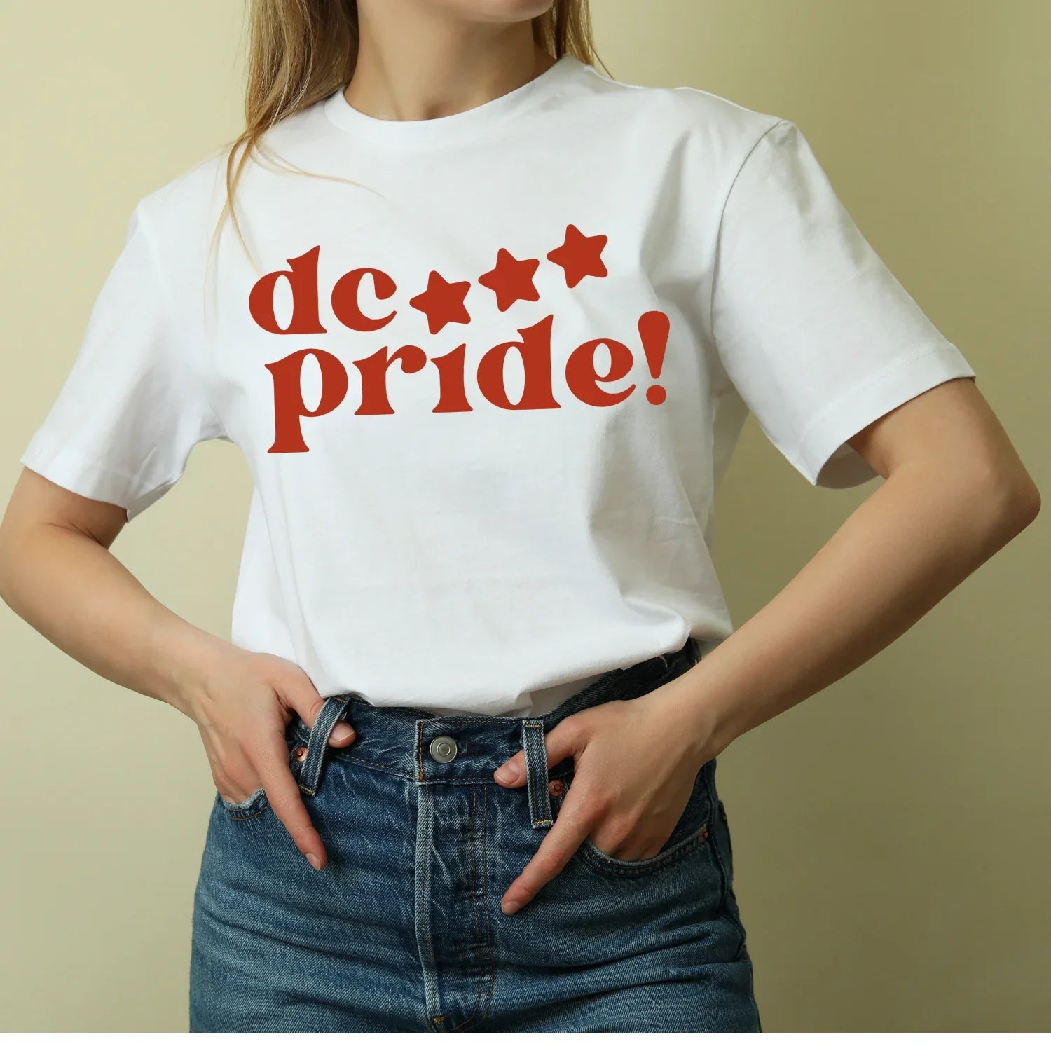 Woman wearing white t-shirt with red 'dc pride!' stars graphic, sustainable kids clothing brand