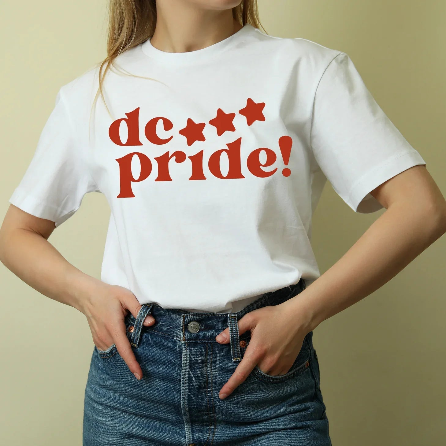 Woman wearing white t-shirt with red 'dc pride!' stars graphic, sustainable kids clothing brand