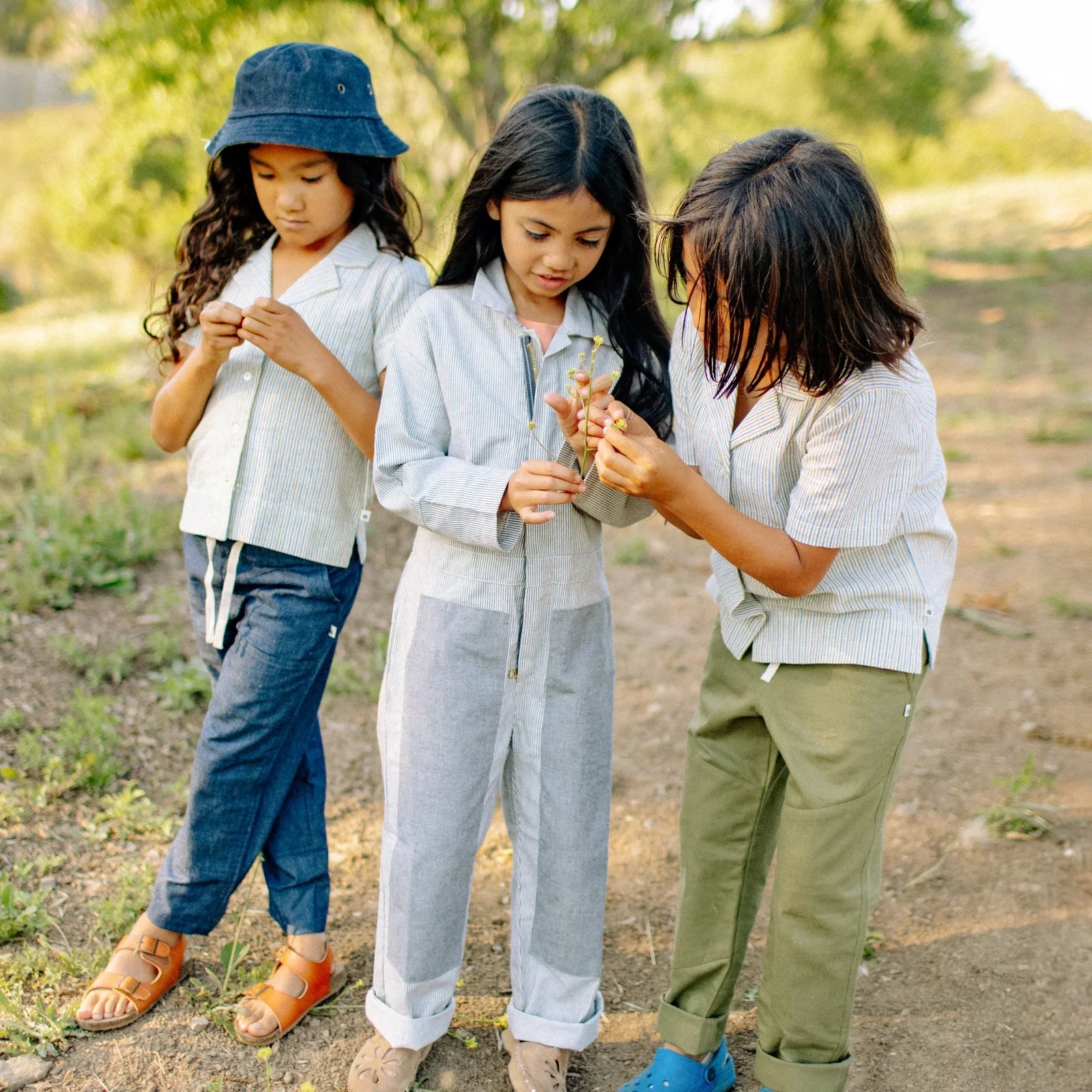 Three kids wearing Jackalo sustainable clothing exploring outdoors on a sunny day