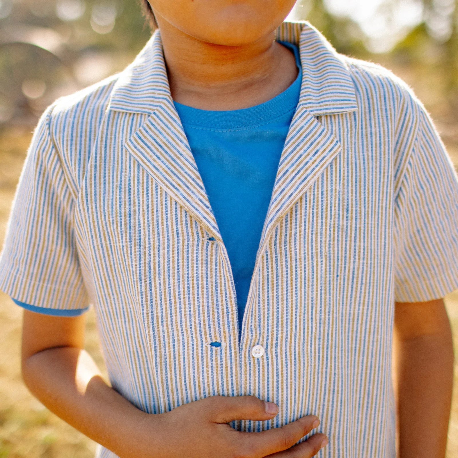 Child in Jackalo striped short sleeve camp shirt and blue tee outdoors