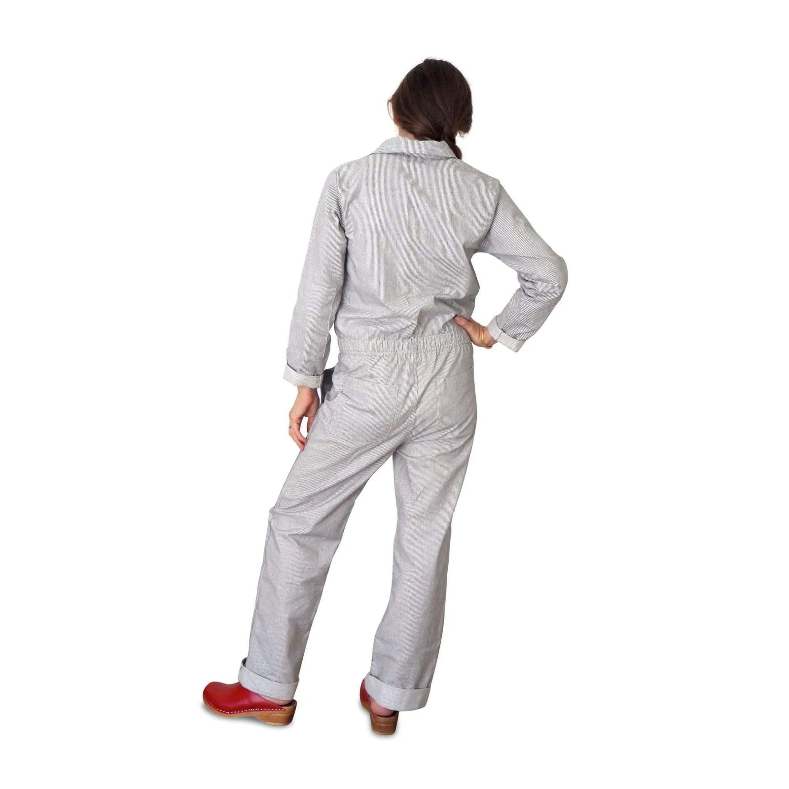 Back view of woman in light gray Jackalo sustainable coverall with red clogs, white background