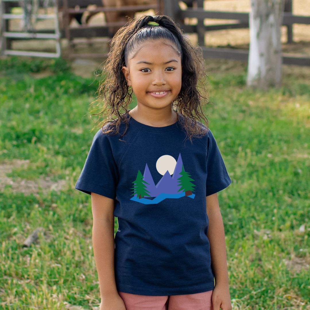 Young girl wearing a navy blue t-shirt with a nature graphic in an outdoor setting