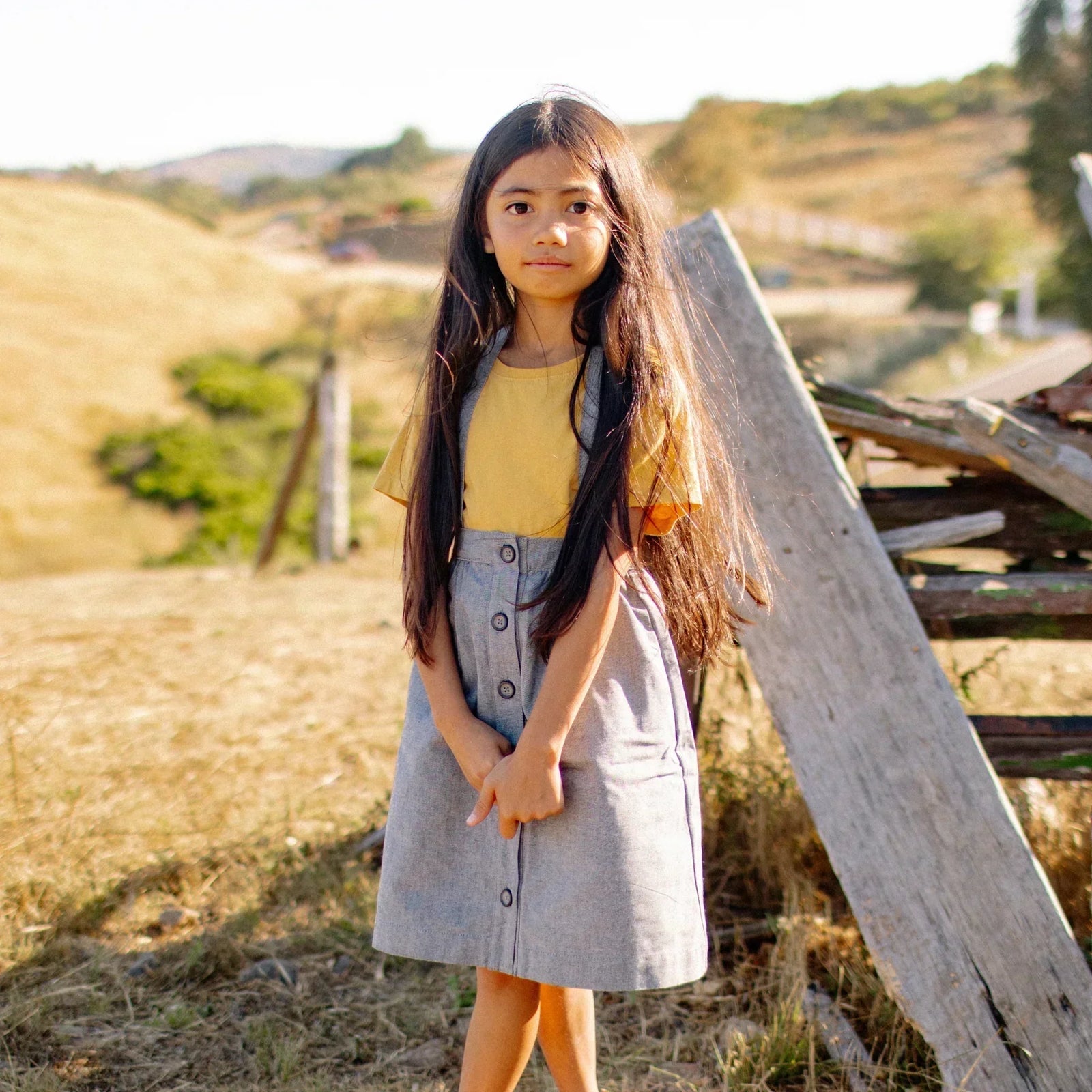 Girl wearing Jackalo sustainable kids skirt and yellow shirt outdoors on a sunny day