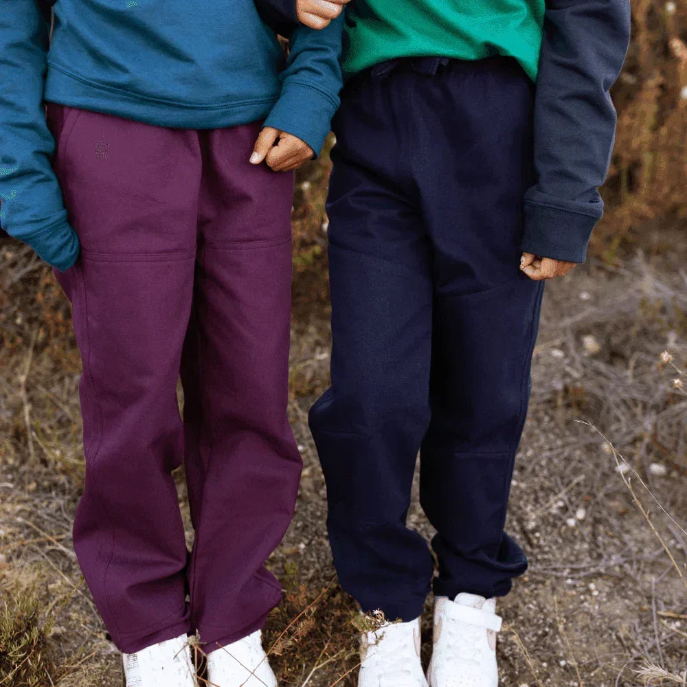Two kids wearing colorful Jackalo sustainable pants for active children outdoors