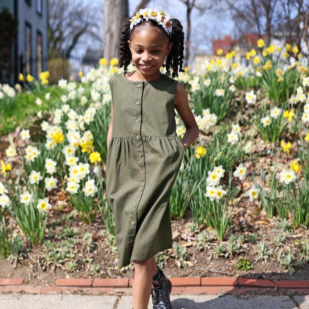 Smiling girl in dark olive sleeveless dress outdoors, Jackalo sustainable kids clothing