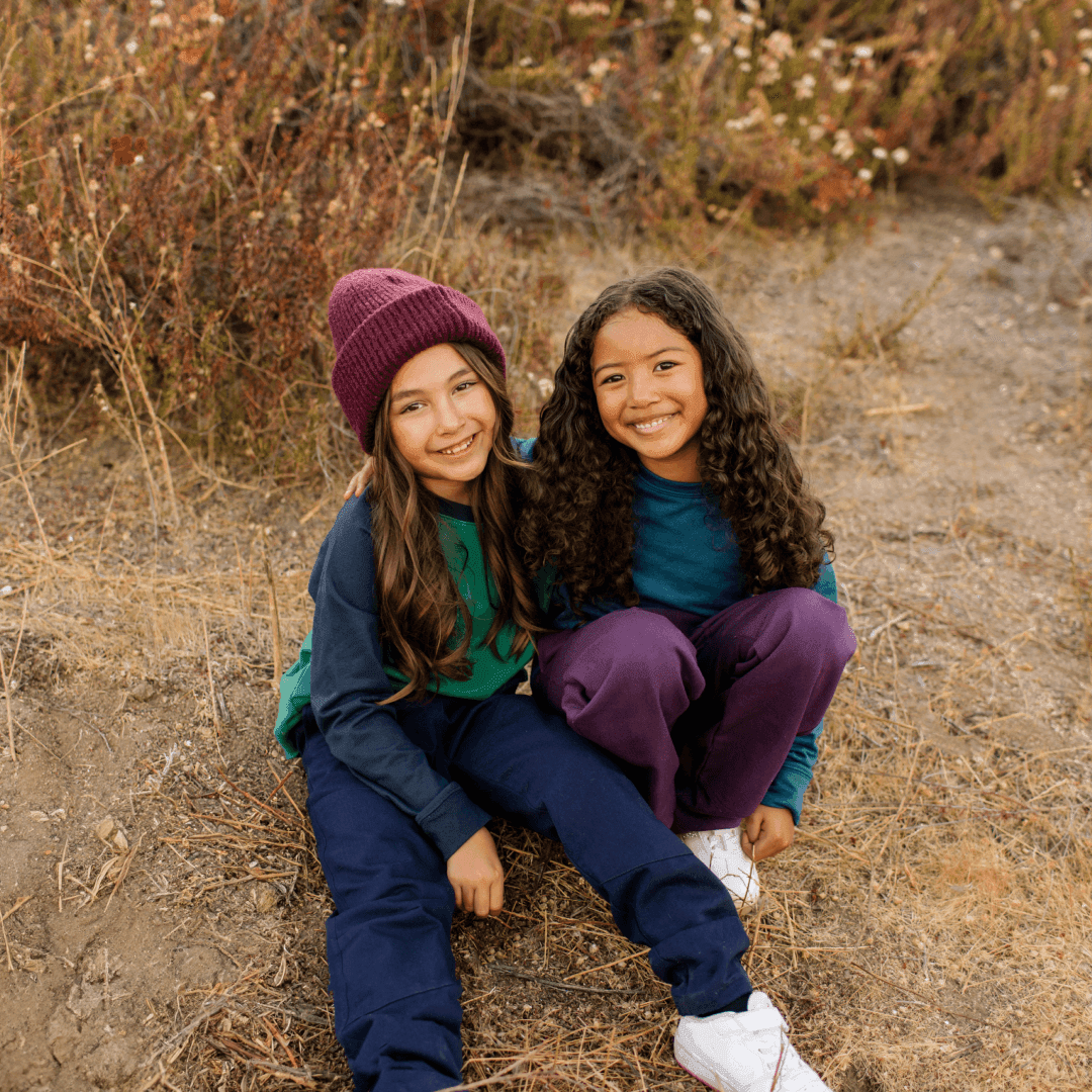 Two smiling kids in Jackalo sustainable pants and tops outdoors on a trail