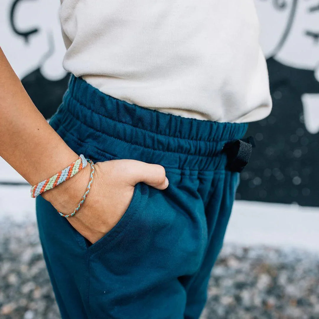Kid wearing blue Jackalo sweatpants with hand in pocket, promoting sustainable kids clothing
