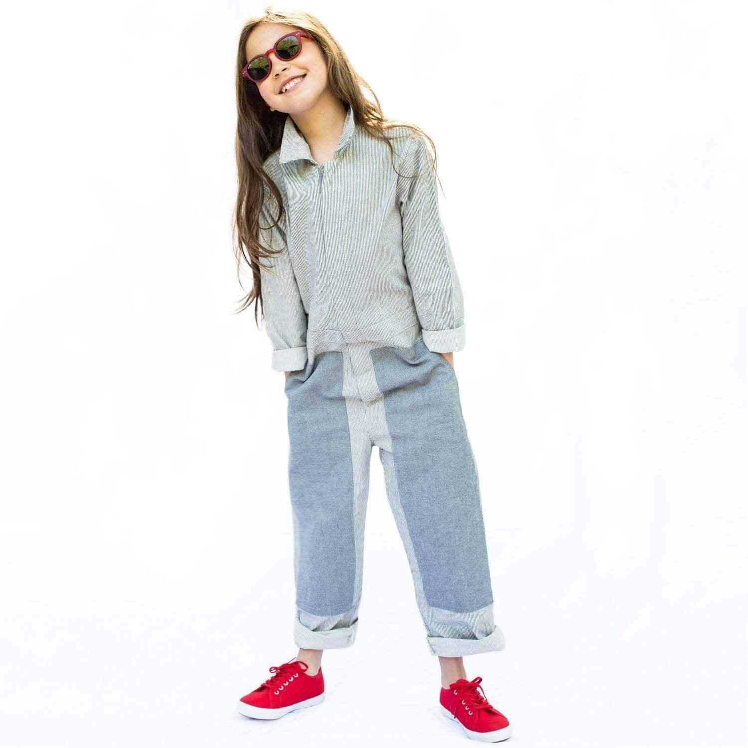 A young girl wearing a glasses, grey shirt and Mac Coverall