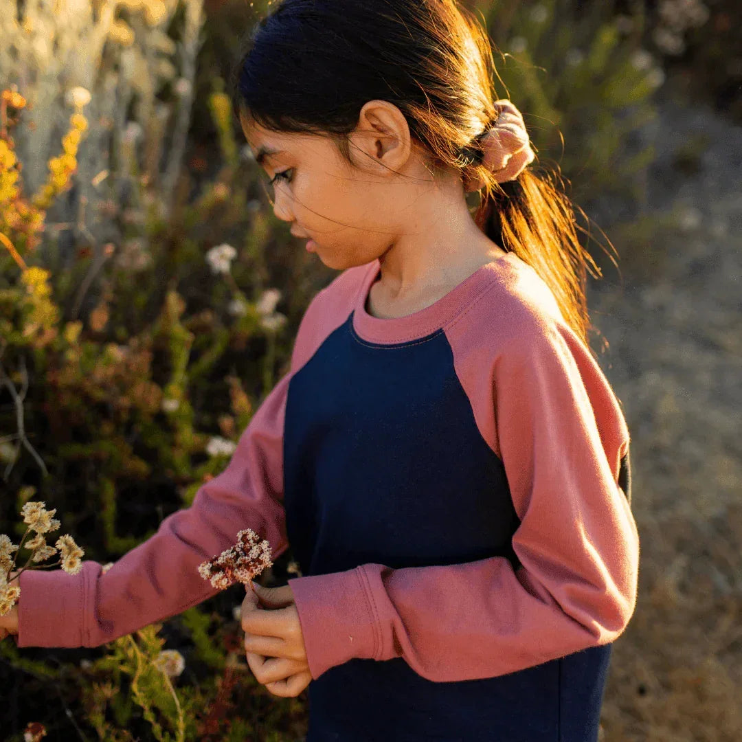 Girl wearing Jackalo sustainable navy and rose raglan shirt outdoors