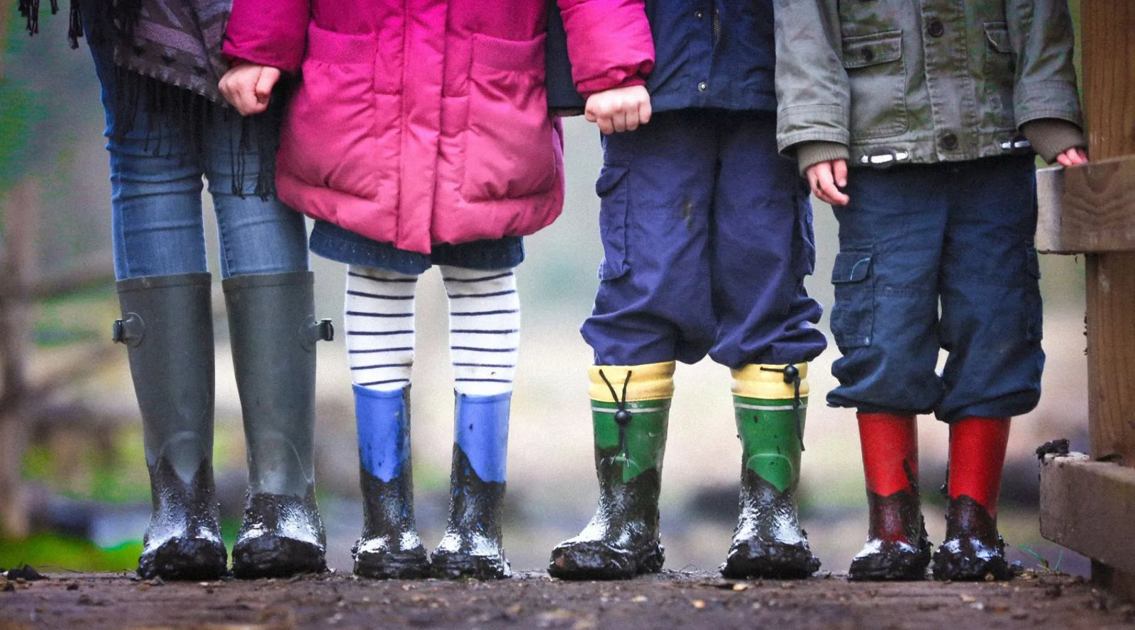 Kids wearing colorful, muddy boots outdoors in Jackalo sustainable clothing