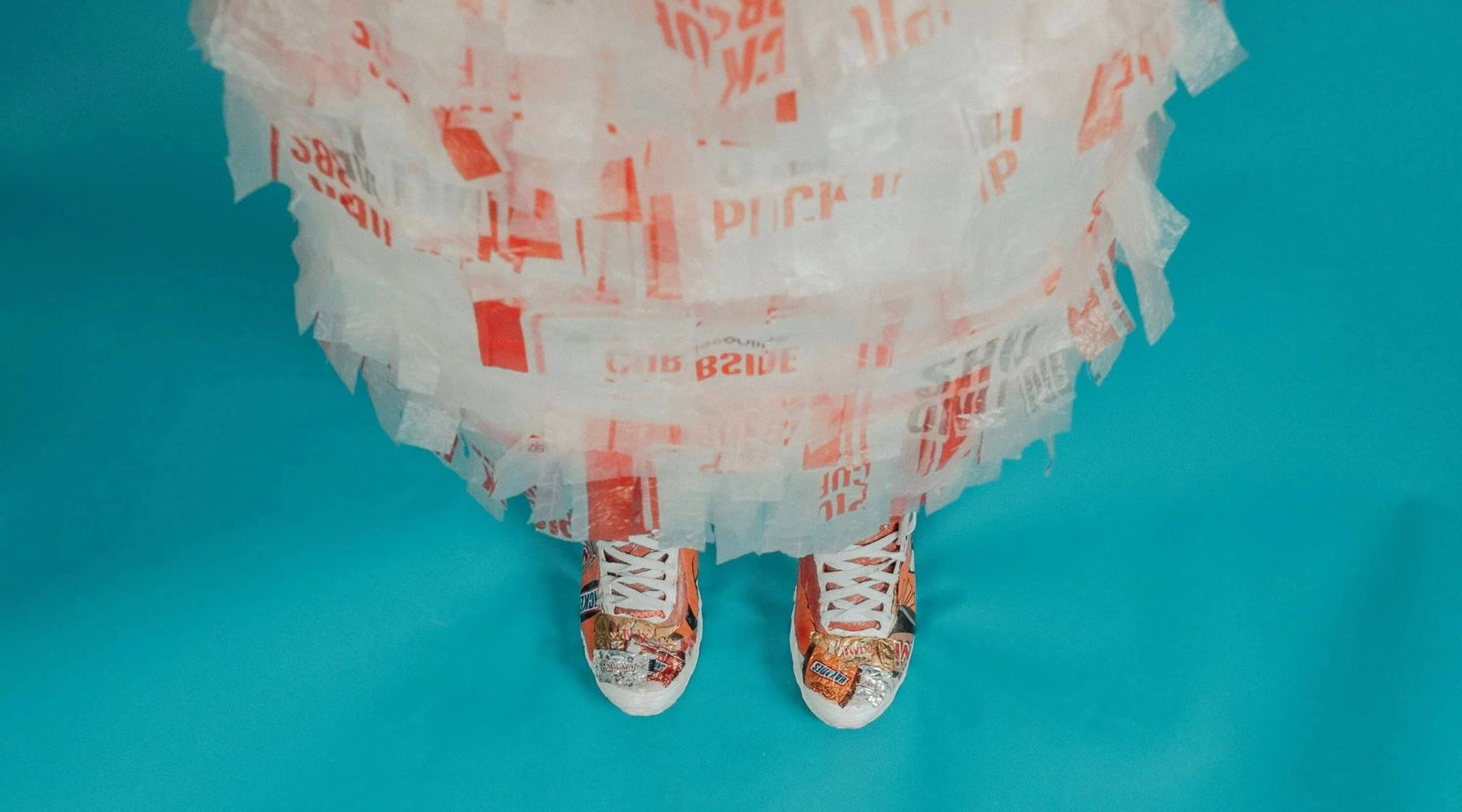 Sustainable kids fashion outfit made from recycled plastic bags and wrappers on blue background