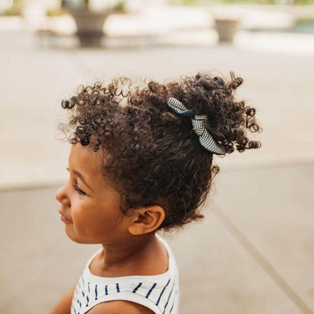 A girl with curly hair wearing a bow hair tie