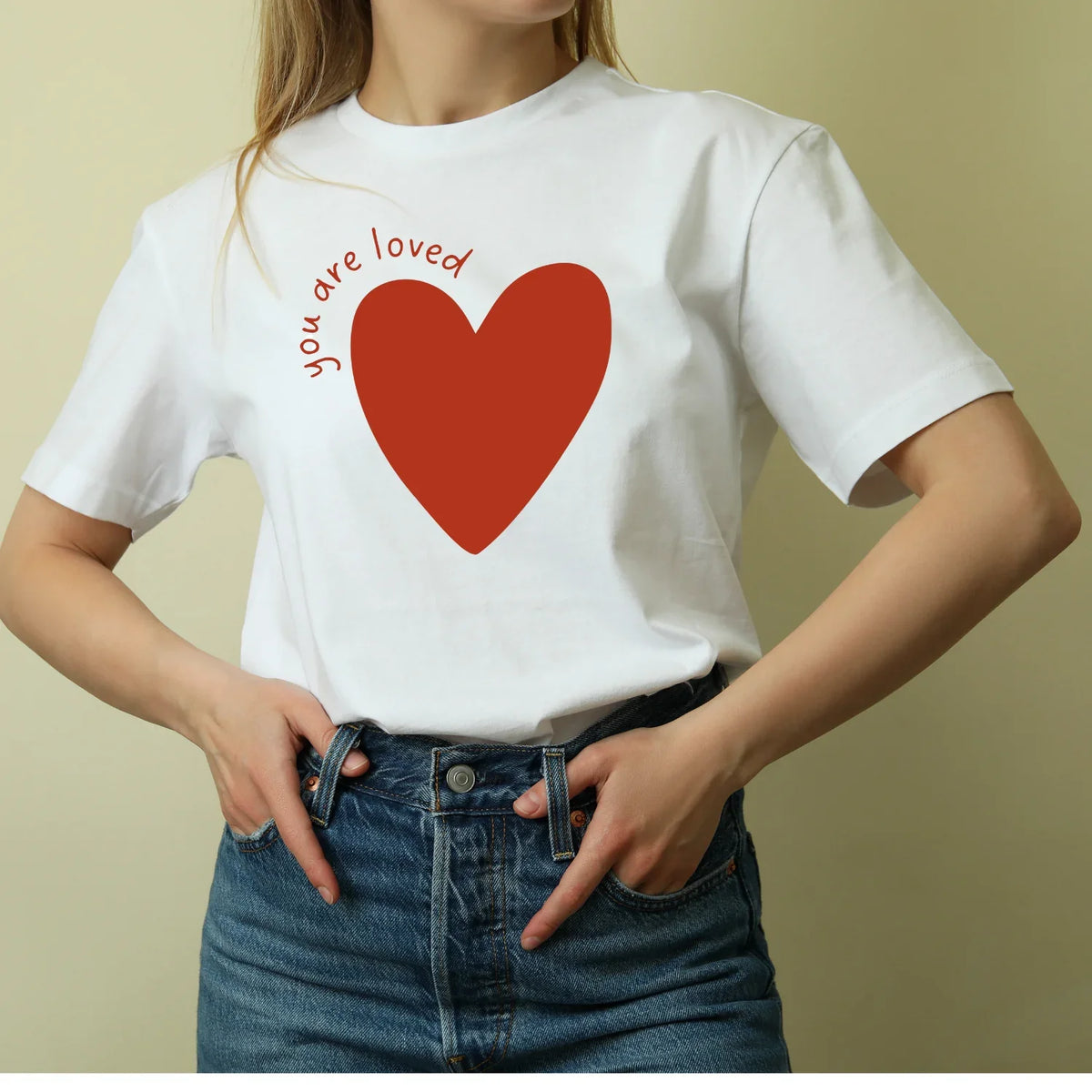 Woman wearing Jackalo white t-shirt with red heart and 'you are loved' text, sustainable kids clothing