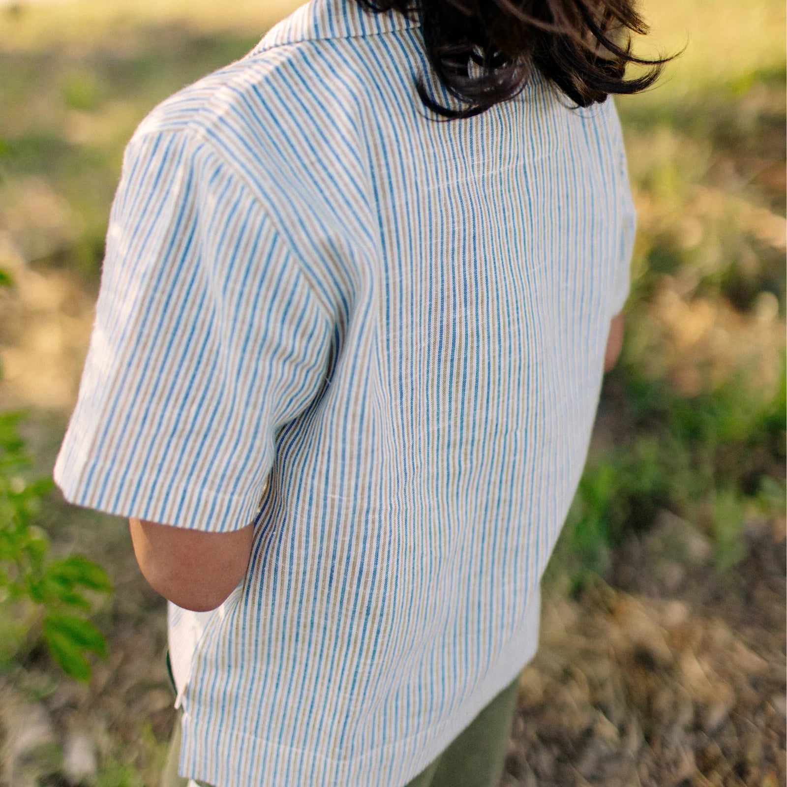 Child wearing Jackalo striped camp shirt outdoors, sustainable kids clothing