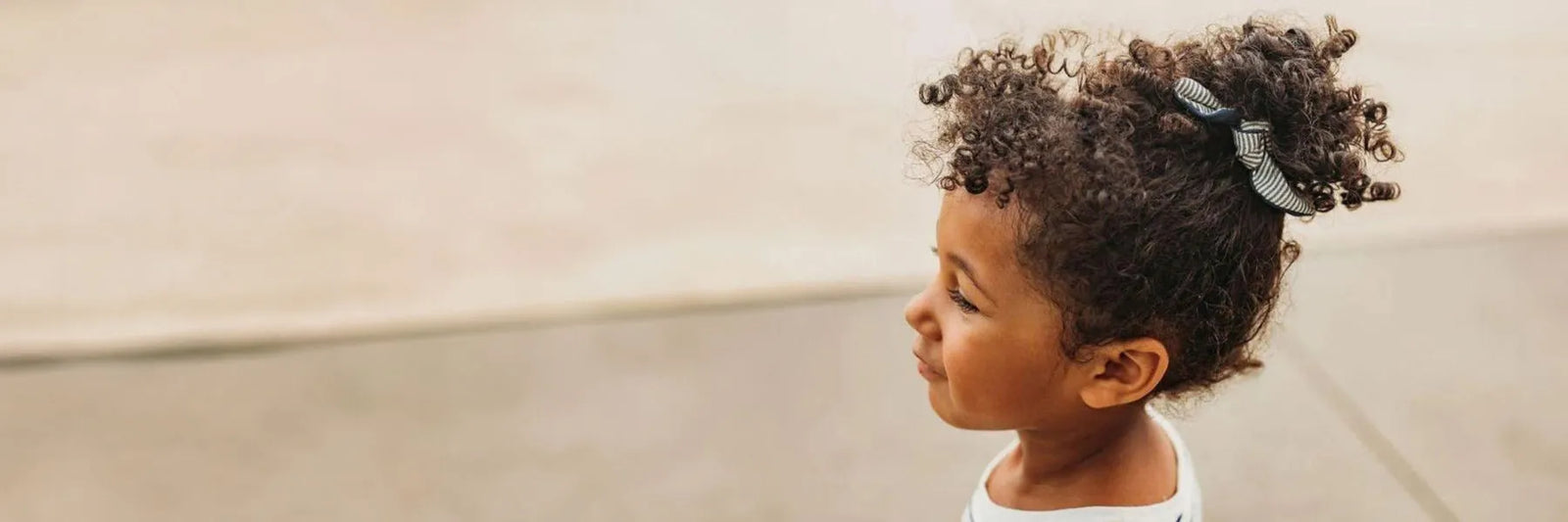 A girl with curly hair wearing a bow hair tie