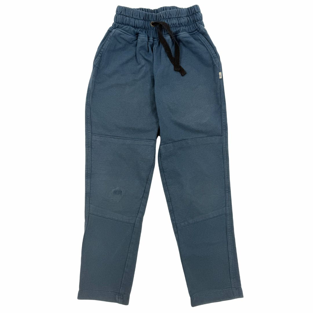 Cropped photo of a kid wearing white shirt and dark blue sweatpants