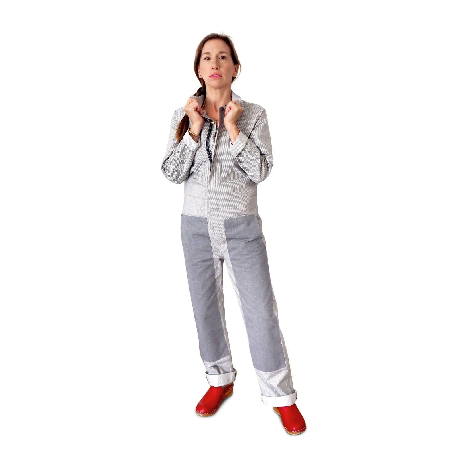 Woman wearing sustainable Jackalo grey coverall and red clogs on white background