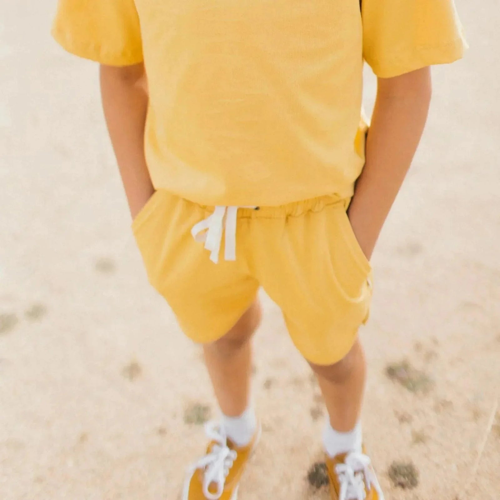 Active kid wearing yellow Jackalo Ollie shorts and matching top outdoors
