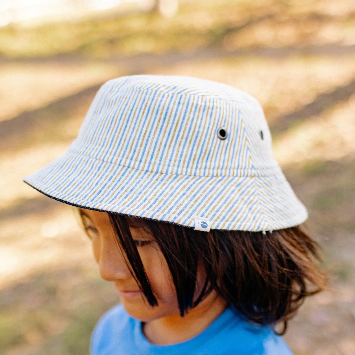 Child wearing Jackalo reversible striped bucket hat outdoors, sustainable kids clothing