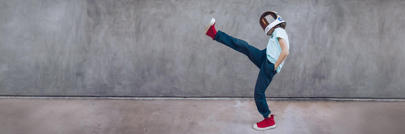 A boy wearing an astronaut helmet kicks up into the air