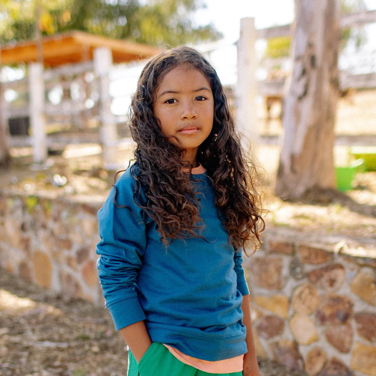 Child wearing a blue Jackalo sweatshirt outdoors, showcasing sustainable kids clothing