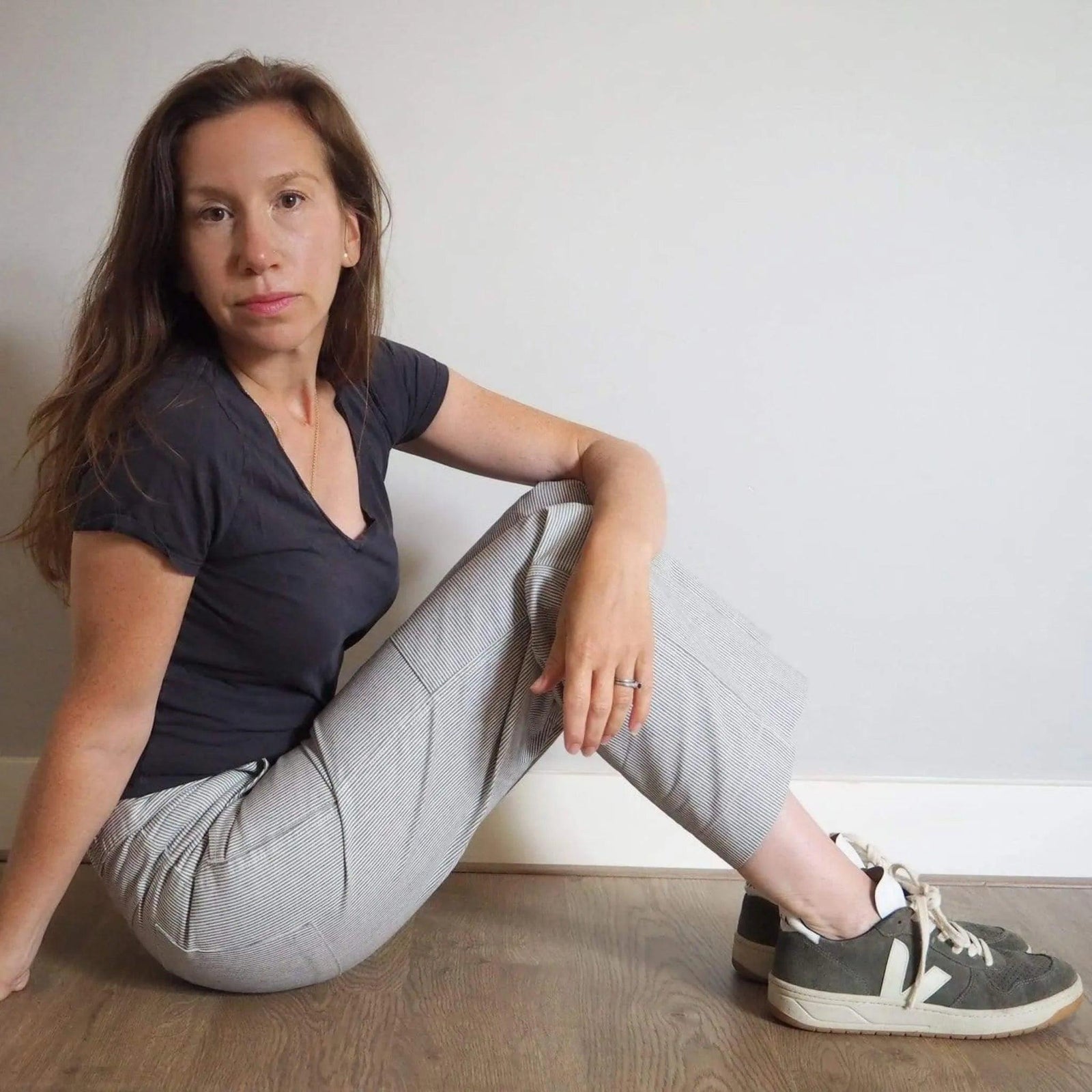 Woman wearing striped Charlie Pants by Jackalo, sitting indoors on wooden floor