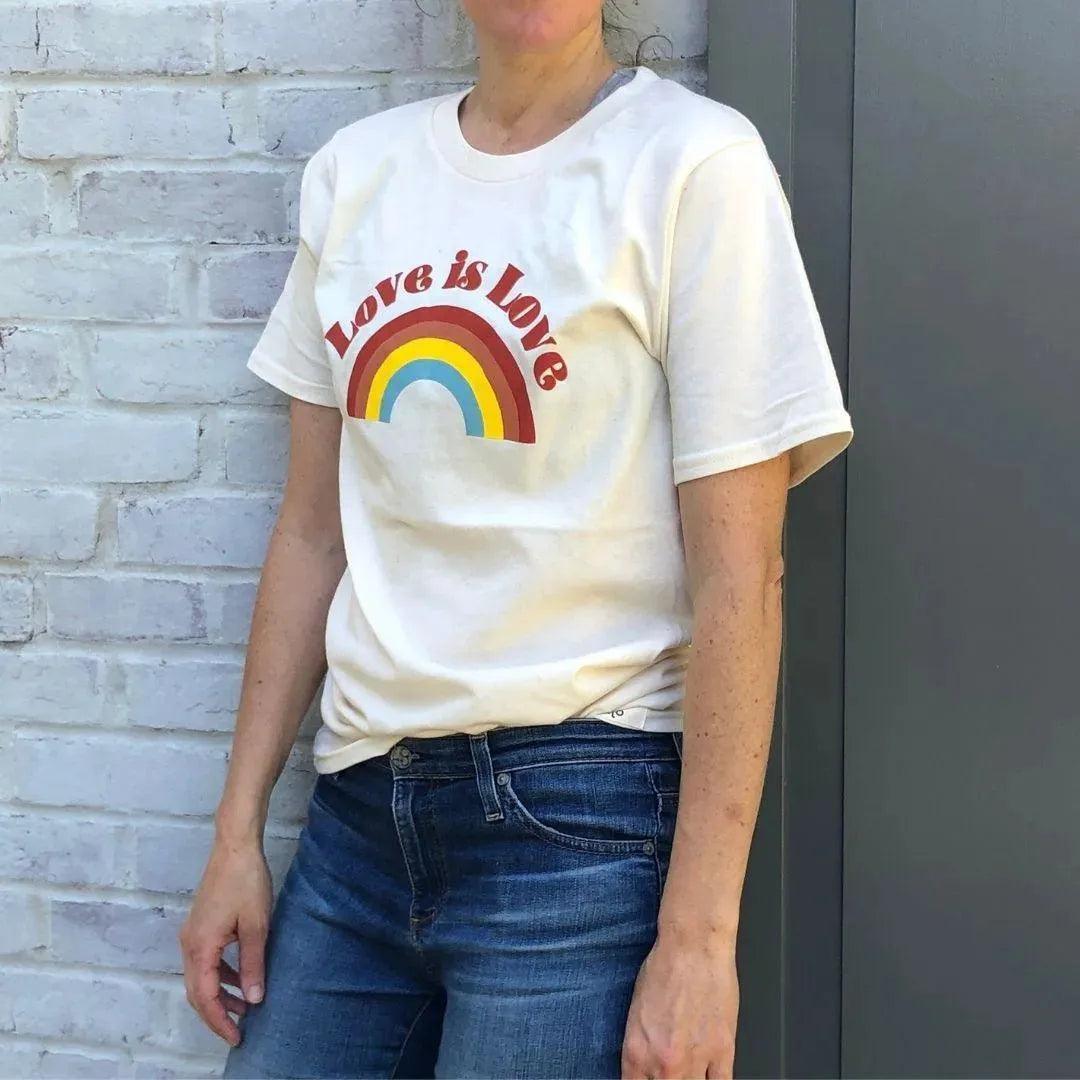 Person wearing Jackalo Love is Love t-shirt with rainbow graphic, sustainable casual wear