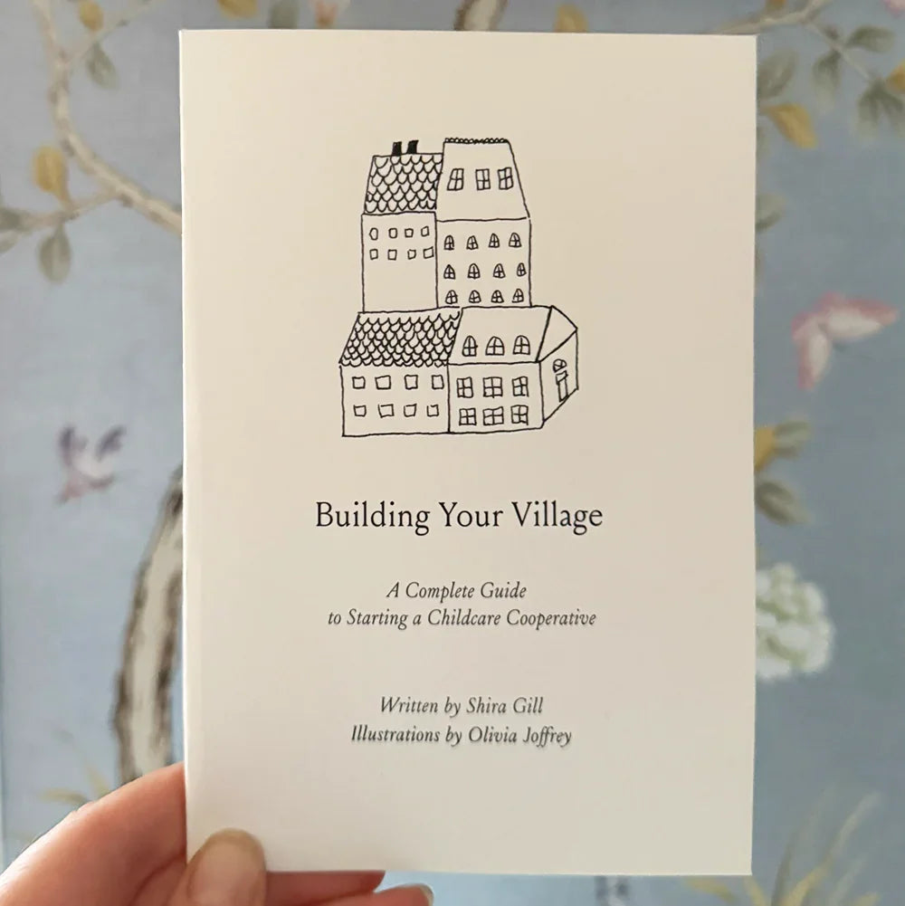 Hand holding 'Building Your Village' childcare cooperative booklet, Jackalo sustainable kids brand