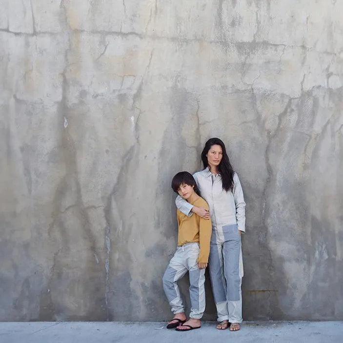 Woman and child in Jackalo sustainable clothing standing against concrete wall