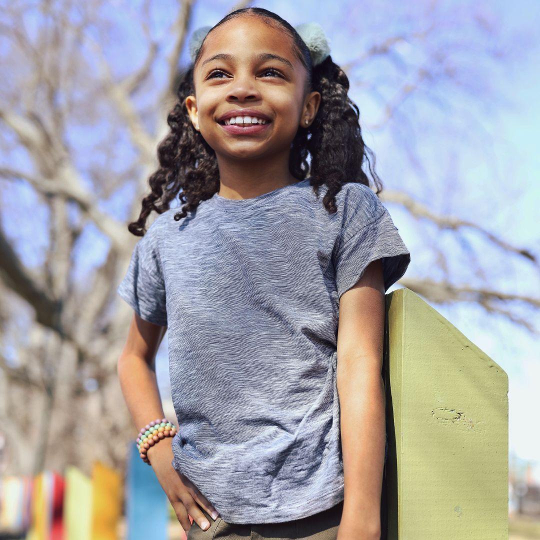 Smiling child wearing a navy space dye Brooklyn t-shirt by Jackalo outdoors in sunlight