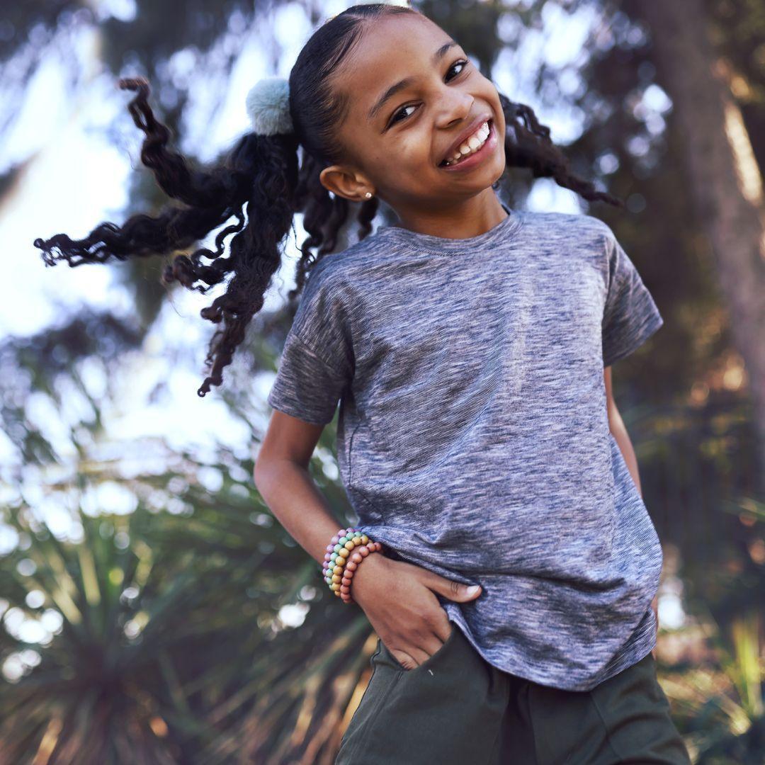 Smiling girl wearing a navy space-dye Brooklyn T-shirt by Jackalo, outdoors among trees
