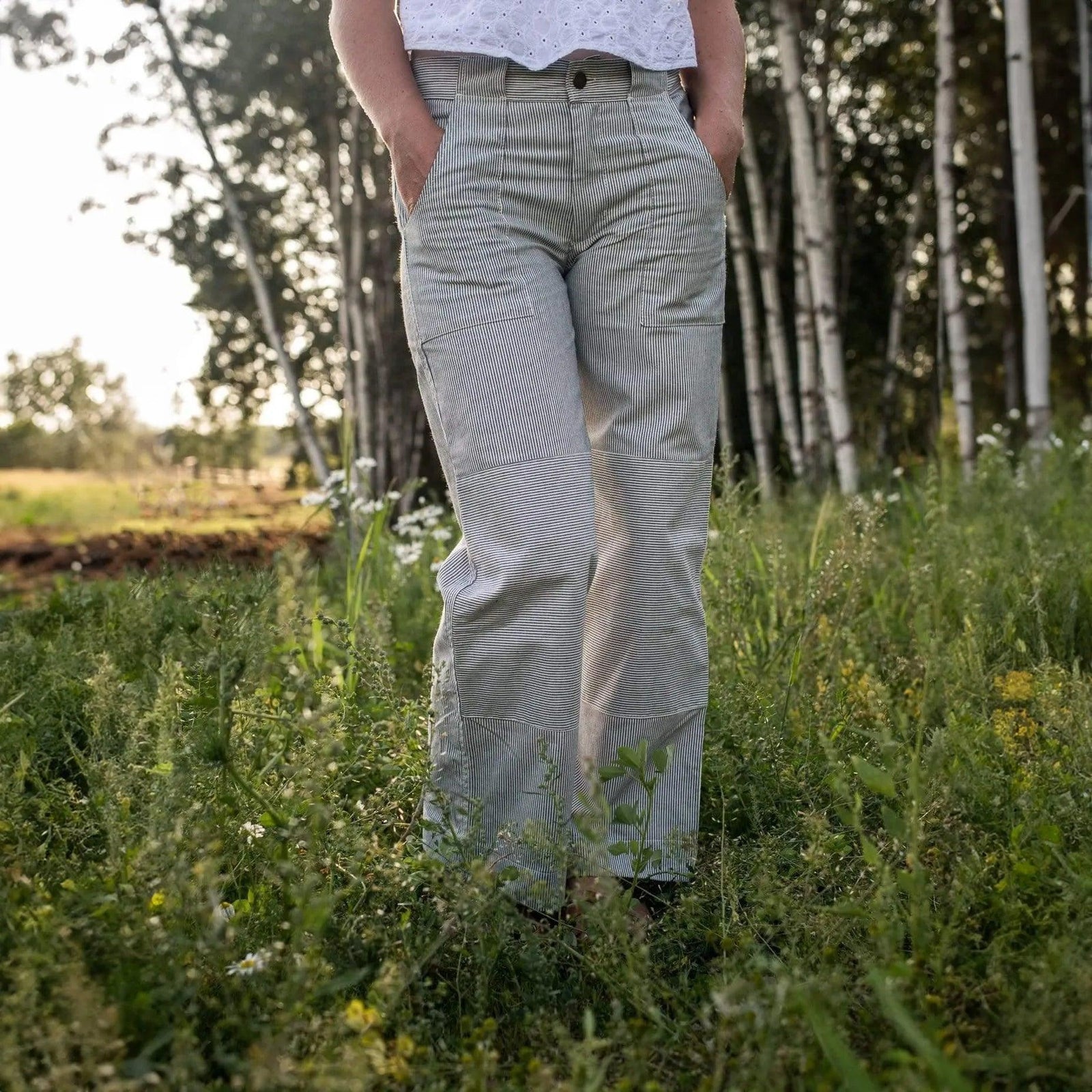 Woman wearing sustainable striped Charlie pants by Jackalo, standing in a grassy field